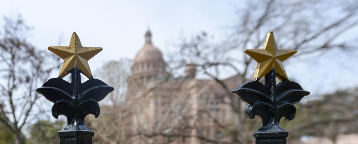 Texas Capitol in background with brass stars from the Capitol fence in foreground